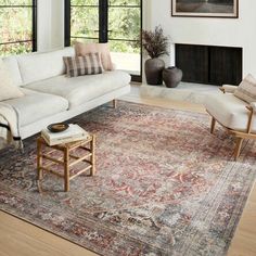 a living room filled with furniture and a large rug on top of a hard wood floor