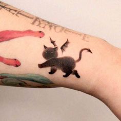 a person with a cat tattoo on their left arm and the words above it are cats