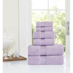 a stack of purple towels sitting on top of a white counter next to a window