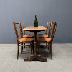 a wooden table with four chairs and a wine bottle sitting on top of the table