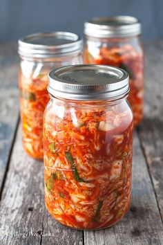 three jars filled with food sitting on top of a wooden table