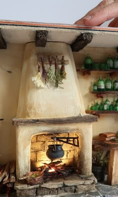 A miniature of an old kitchen with a stone fireplace, dried herbs, green bottles and a stone floor. Witch's kitchen Tudor Dollhouse Interior, Fairy House Kitchen, Diy Dollhouse Wall Art, Miniature Diaroma, Fairy Fireplace, Old Stone Fireplace, Old Chimney, Cabin Dollhouse, Mini Fireplace