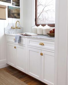 a kitchen with white cabinets and gold handles