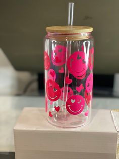 two tumblers sitting on top of a box with straws in them and hearts painted on the lids