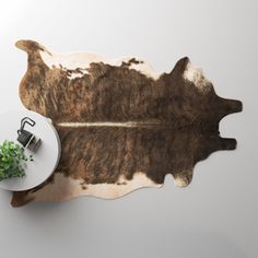 a cowhide rug with a plant on it next to a white table and chair