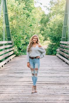 a woman standing on a bridge wearing ripped jeans