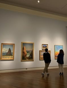 people looking at paintings on display in an art gallery