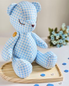 a blue and white teddy bear sitting on top of a wooden tray with buttons around it