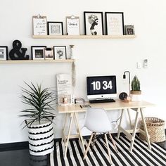 a white desk topped with a computer next to a black and white striped rug