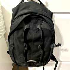 a black backpack sitting on top of a wooden floor next to a white wall and door