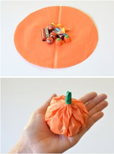 an orange paper pumpkin with candy on top and in the background, there is a hand holding