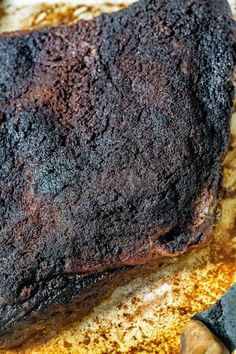 a large piece of meat sitting on top of a pan covered in seasoning next to a knife