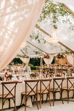 an outdoor tent with tables and chairs set up for a formal dinner or wedding reception