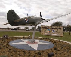 an airplane is on display in the middle of a field with a sign and flags