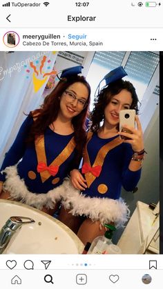 two women dressed in costumes taking a selfie with their cell phone while standing in front of a bathroom sink