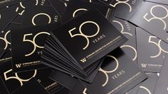 a pile of black and gold business cards with the number fifty six on them, all stacked together