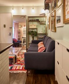 a living room filled with furniture and pictures hanging on the wall next to a kitchen