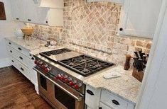 a stove top oven sitting inside of a kitchen next to white cabinets and counter tops