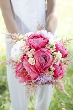 a bride holding a bouquet of pink and white flowers