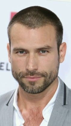 a close up of a person wearing a suit and tie with a goatee on his head