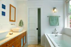 a large white bath tub sitting next to a sink in a bathroom under a window