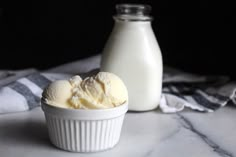 two scoops of ice cream next to a bottle of milk on a marble surface