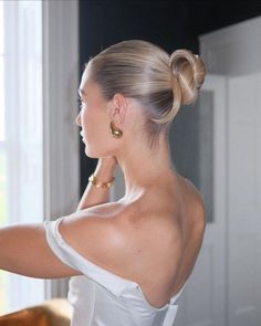 a woman in a white top is looking out the window with her hand on her shoulder