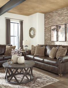 a living room filled with furniture and a brick wall behind the couch is a coffee table