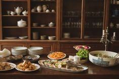 a wooden table topped with plates and bowls filled with different types of food on top of it