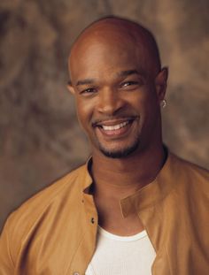 a smiling man in a tan jacket and white t - shirt