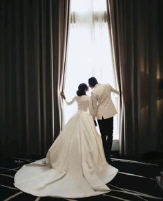 a bride and groom standing in front of a window