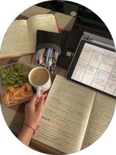 a person holding a cup of coffee in front of an open book on a table