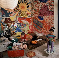 two children sitting on the floor in front of a colorful wall