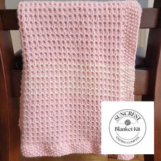 a pink knitted blanket sitting on top of a wooden chair