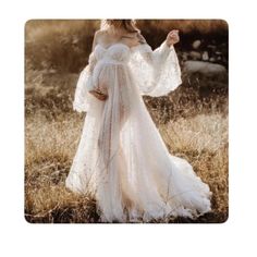 a woman in a white dress is standing in the grass with her arms outstretched and looking off to the side