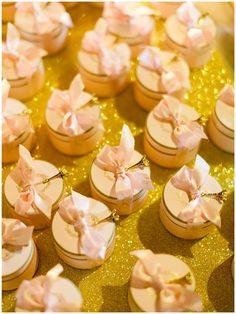 small cookies with pink bows on them sitting on a gold tray covered in confetti