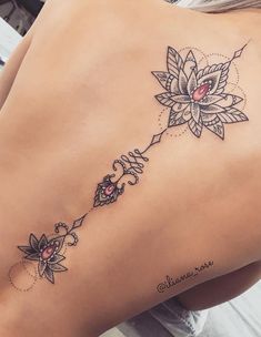 the back of a woman's stomach with tattoos on her ribs and flowers in the middle