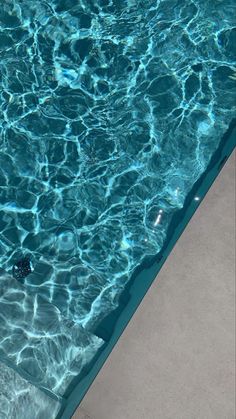 an umbrella sitting on the edge of a swimming pool with clear blue water in it