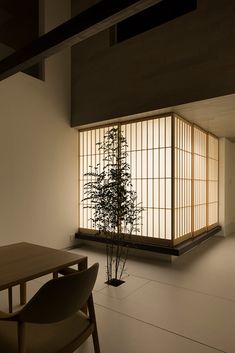 an empty room with a table and chair next to a bamboo plant on the floor