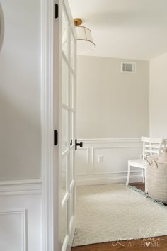 an empty room with white walls and wood flooring is seen through the door to another room