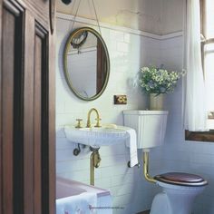 a white toilet sitting next to a sink in a bathroom under a mirror above a window