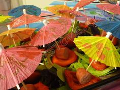 several colorful umbrellas are placed on top of lettuce and carrots in a container