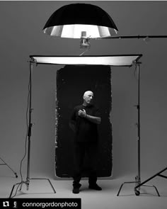 a black and white photo of a man standing in front of a light