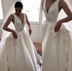 a woman in a white wedding dress standing next to a window