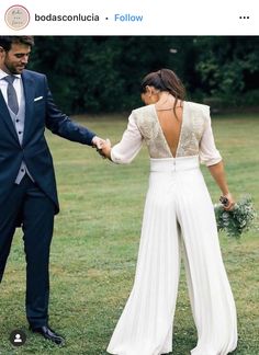 a bride and groom holding hands in the grass