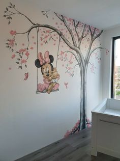 a child's room painted in pink and white with mickey mouse on the swing