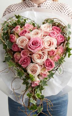 a woman holding a heart shaped bouquet of pink roses