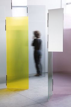 a man is standing in front of three colorful partitions with his back to the camera