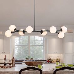 a kitchen with white cabinets and an island in front of a window that has lights hanging from the ceiling