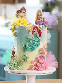 there is a cake decorated with princesses on the top and bottom tiers that are multicolored